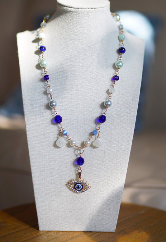 Necklace with an eye pendant on a white mannequin bust
